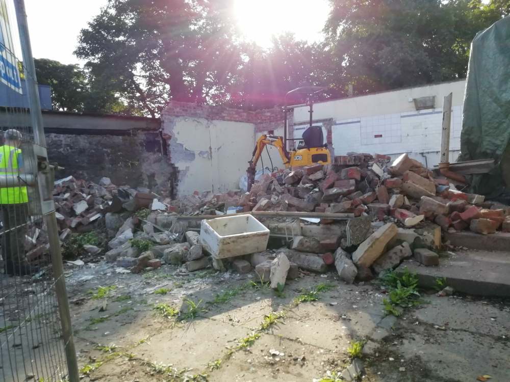 Site-with-back-wall-showing-and-rubble-and-digger-at-front